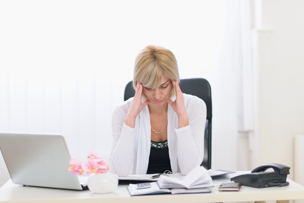 Stressed middle age business woman sitting at office table